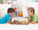 Two boys playing chess laying on the floor and thinking hard